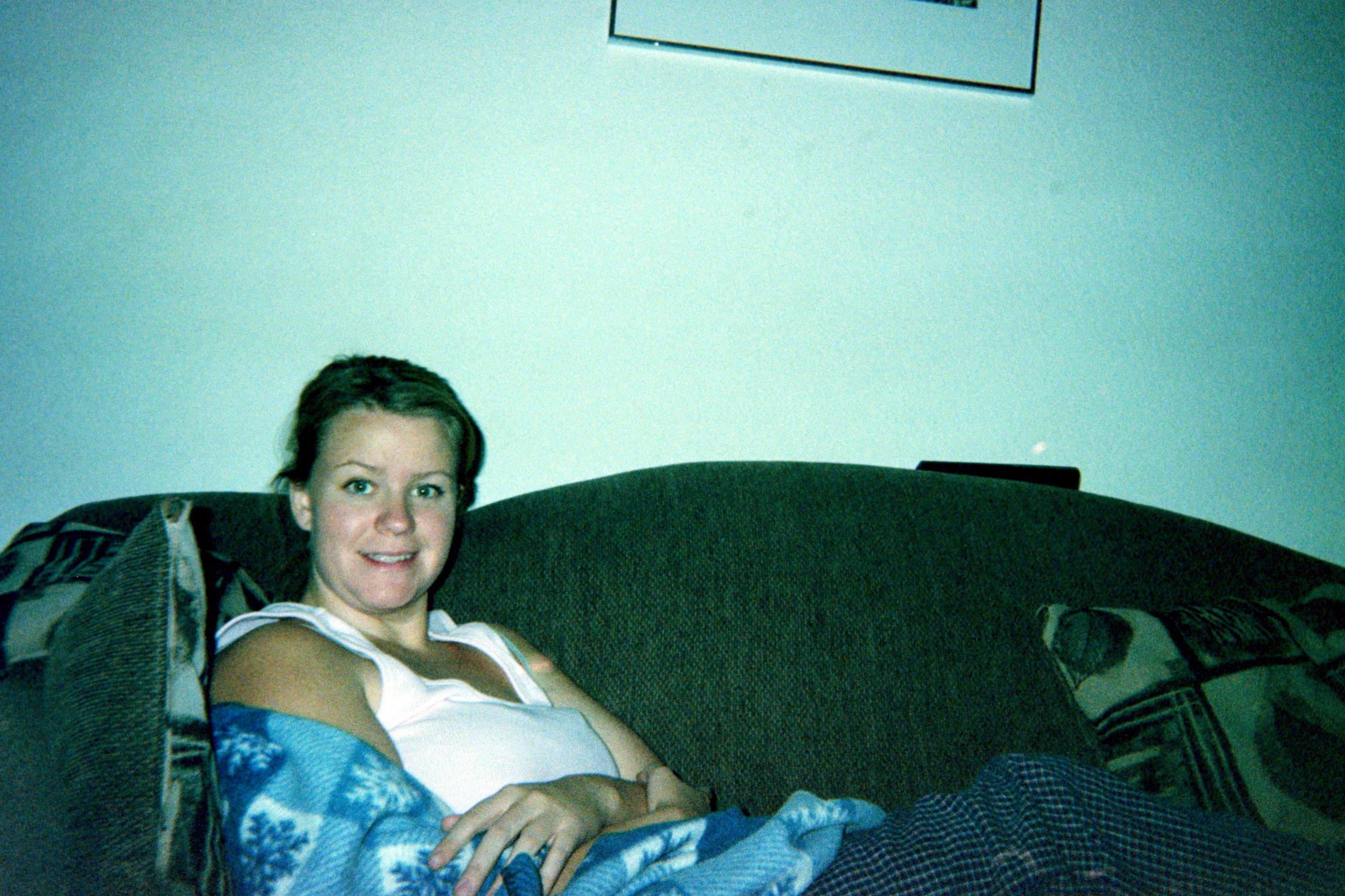 An old photo from the early 2000s of Kori on the couch, smiling at the camera.